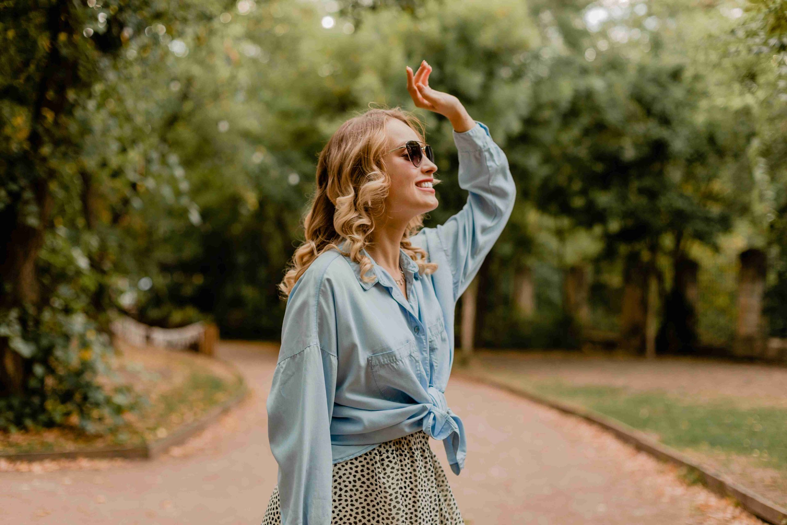 attractive-blond-smiling-woman-walking-park-summer-outfit_11zon